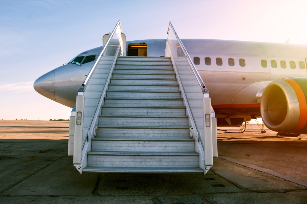 Passenger plane in the morning sun, with the boarding stairs leading to the entrance