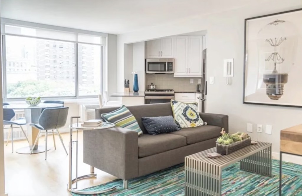 A living room with a bed and a table in a one -bedroom apartment at 460 2 Ave. Manhattan, NY